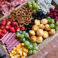 charcuterie board for kids with cheese cubes, mini muffins, pretzels, strawberries, salami, grapes