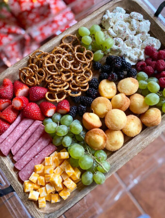 charcuterie board for kids with cheese cubes, mini muffins, pretzels, strawberries, salami, grapes