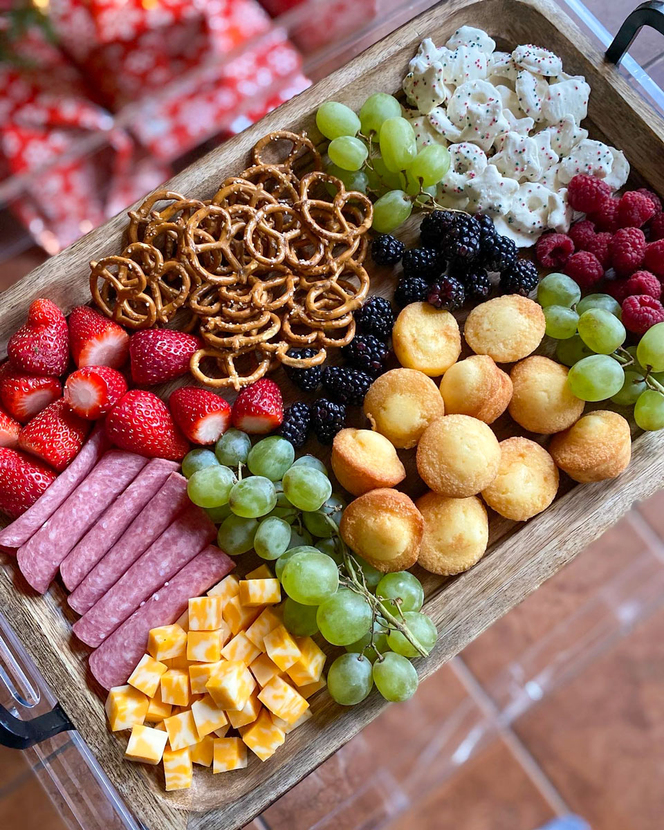 charcuterie board for kids with cheese cubes, mini muffins, pretzels, strawberries, salami, grapes